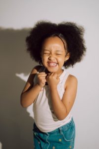 A young girl with an afro laughs heartily laughs